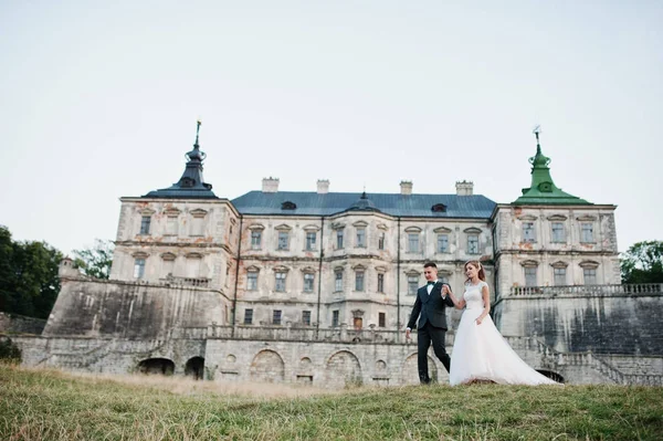 Fabuloso casal de casamentos posando na frente de um velho castelo medieval — Fotografia de Stock