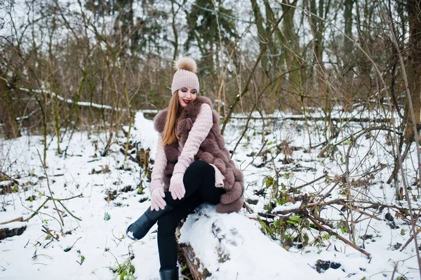 Chica con estilo en abrigo de piel y ropa de cabeza en el bosque de invierno . — Foto de Stock