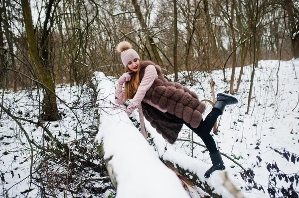 Stylisches Mädchen in Pelzmantel und Kopfbedeckung im Winterwald. — Stockfoto
