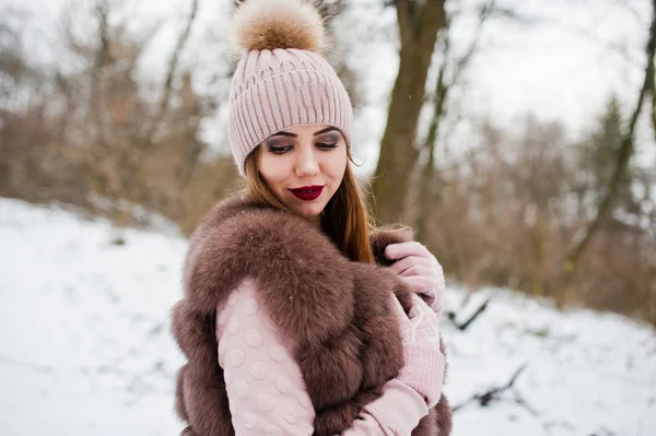 Stylisches Mädchen in Pelzmantel und Kopfbedeckung im Winterwald. — Stockfoto