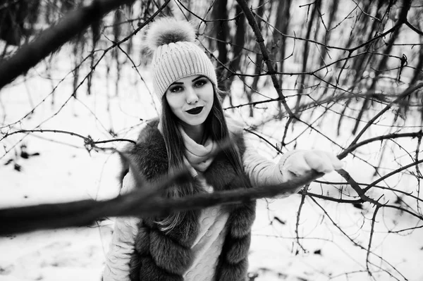 Stijlvolle meisje in bontjas en hoofddeksels bij winter forest. — Stockfoto