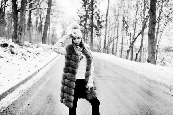 Stylish girl in fur coat and headwear at winter day on road. — Stock Photo, Image