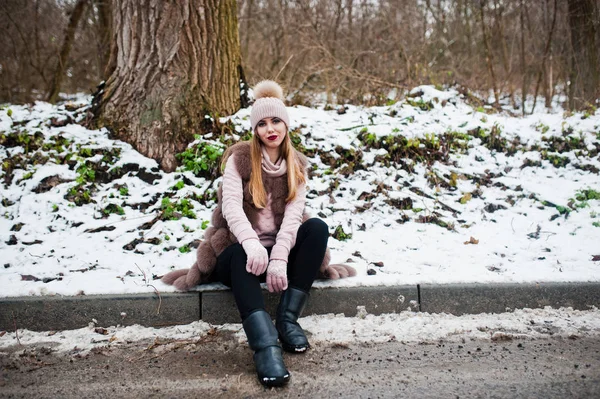 Стильная девушка в шубе и головном уборе в зимний день на сидячем месте — стоковое фото