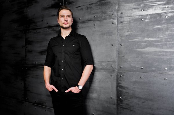Studio portrait of stylish man wear on black shirt against steel