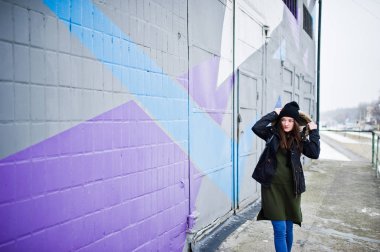 Genç kız renkli duvara karşı soğuk günde oluşturuyordu..