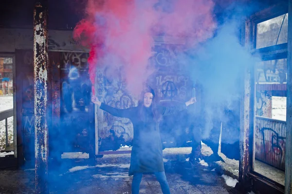 Young girl with blue and red colored smoke bomb in hands.