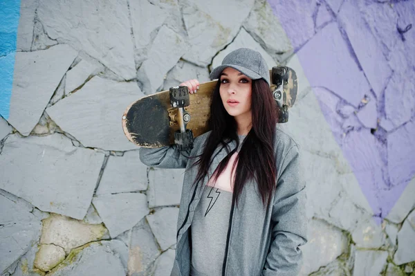 Élégante fille brune en casquette grise, style de rue décontracté avec skate — Photo