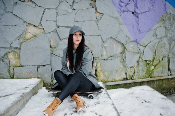 Stijlvolle brunette meisje in grijze dop, casual straat stijl met skat — Stockfoto