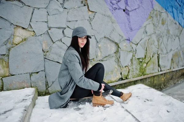 Стильна брюнетка в сірій шапці, випадковий вуличний стиль зі скейтом — стокове фото