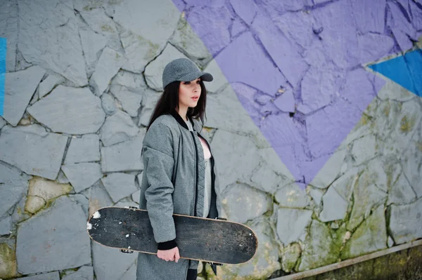 Stijlvolle brunette meisje in grijze dop, casual straat stijl met skat — Stockfoto