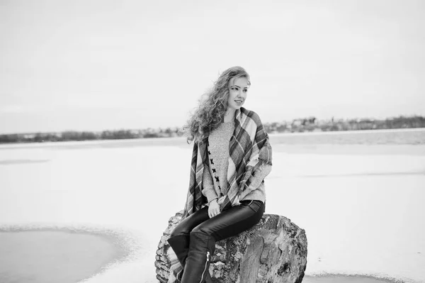 Curly blonde girl in checkered plaid against frozen lake at wint — Stock Photo, Image
