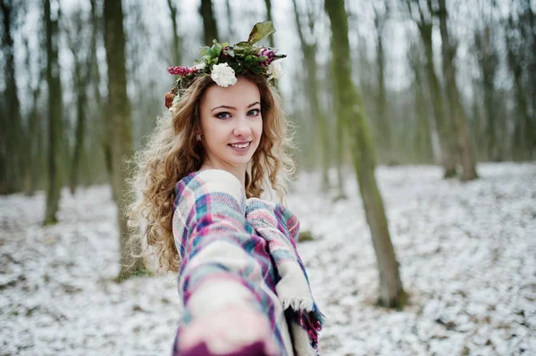 Kudrnatá roztomilá blondýnka s věncem v kostkovaný pléd na zasněžené f — Stock fotografie