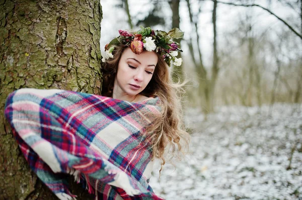 Krullend schattige blonde meisje met krans in geruite plaid op besneeuwde f — Stockfoto