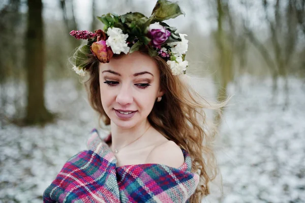 Kudrnatá roztomilá blondýnka s věncem v kostkovaný pléd na zasněžené f — Stock fotografie