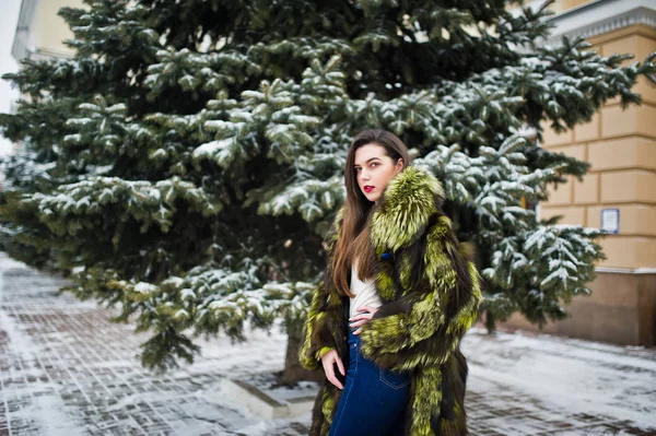 Bruna ragazza in pelliccia verde nella giornata invernale contro il pino nevoso — Foto Stock