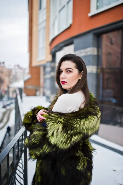 Brunette fille en manteau de fourrure vert à la rue de la ville contre la maison — Photo