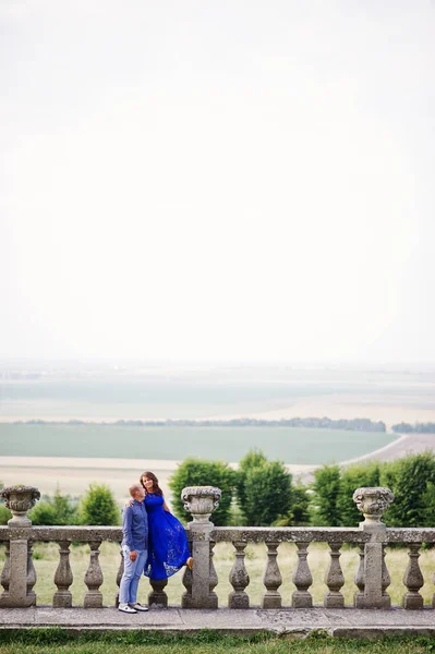 Hermosa pareja enamorada contra el viejo castillo. Chica en vestido azul . — Foto de Stock