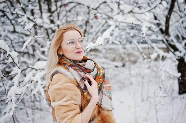 Portraiy of blonde girl in glasses, red fur coat and scarf at wi — Stock Photo, Image