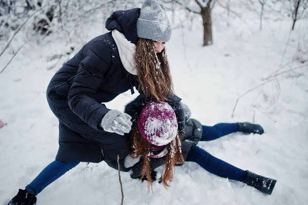 Dwaj przyjaciele śmieszne dziewczyny zabawy w zimowy śnieżny dzień w pobliżu śnieg — Zdjęcie stockowe