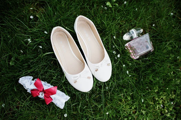 Zapatos de novia, perfume y ligas que yacen sobre la hierba . — Foto de Stock