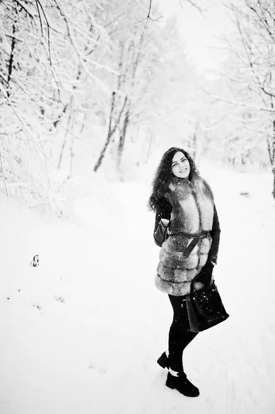 Σγουρό κορίτσι κομψότητα στο γούνινο παλτό και τσάντα στο χιονισμένο δασικό πάρκο — Φωτογραφία Αρχείου