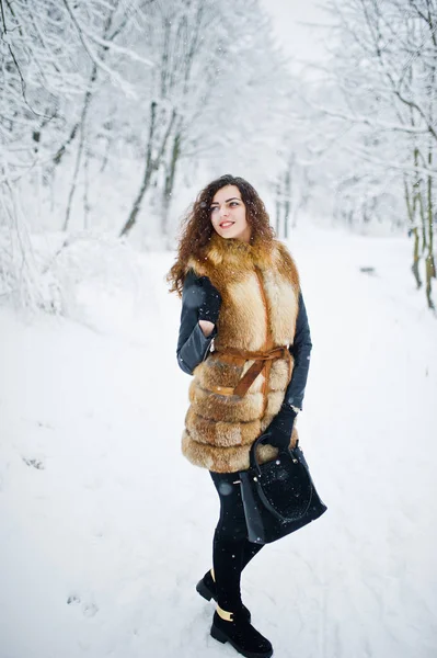 Menina encaracolado elegância em casaco de pele e bolsa no parque florestal nevado — Fotografia de Stock