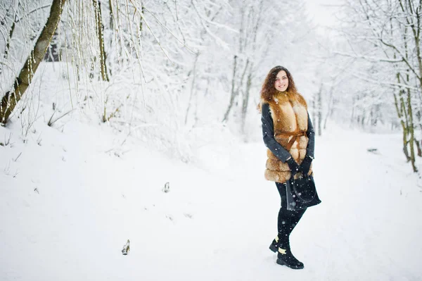 Elégance fille bouclée en manteau de fourrure et sac à main au parc forestier enneigé — Photo