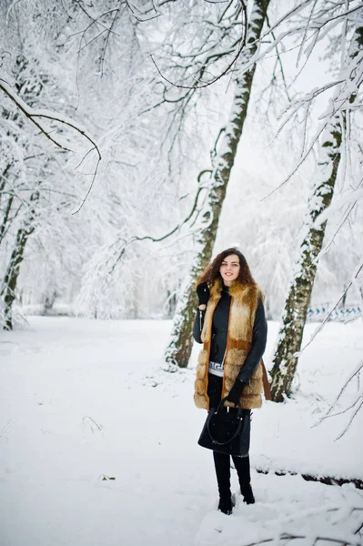 Елегантність кучерявої дівчини в шубці і сумці в засніженому лісовому парку — стокове фото