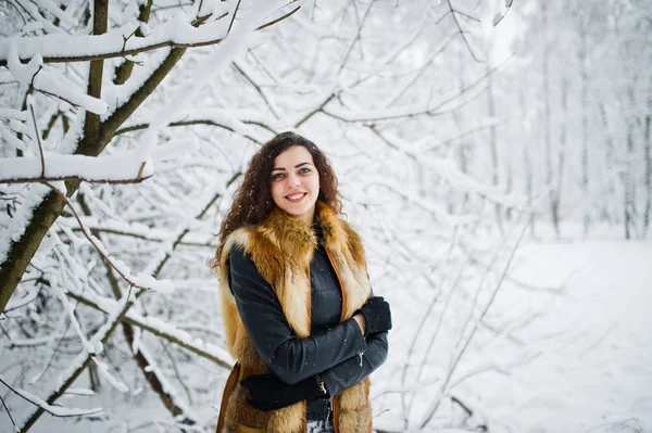 Menina encaracolado elegância em casaco de pele no parque florestal nevado no inverno . — Fotografia de Stock