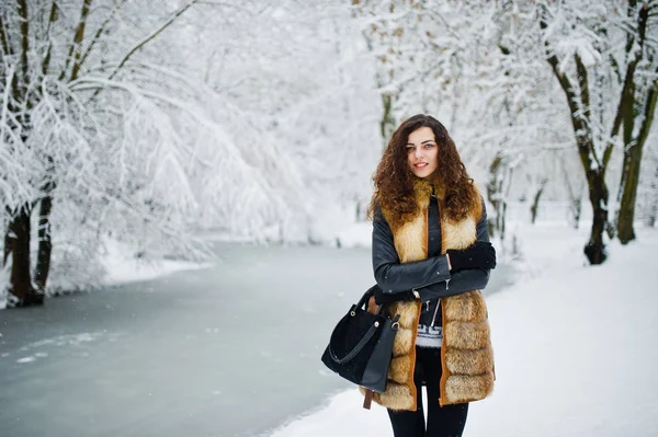 Elegance curly girl in fur coat at snowy forest park at winter. — Stock Photo, Image
