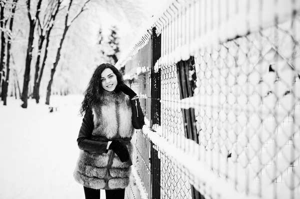 De gekrulde meisje elegantie in bontjas in het besneeuwde forest park op de winter. — Stockfoto