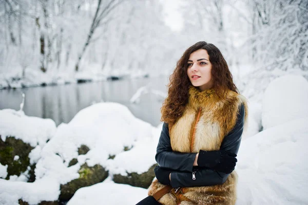 Elégance fille bouclée en manteau de fourrure au parc forestier enneigé en hiver . — Photo
