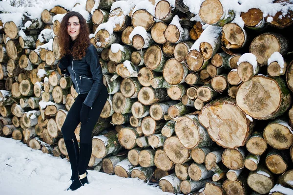 De gekrulde meisje elegantie in lederen jas in het besneeuwde forest park op wi — Stockfoto