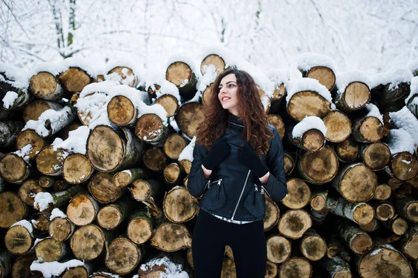 De gekrulde meisje elegantie in lederen jas in het besneeuwde forest park op wi — Stockfoto