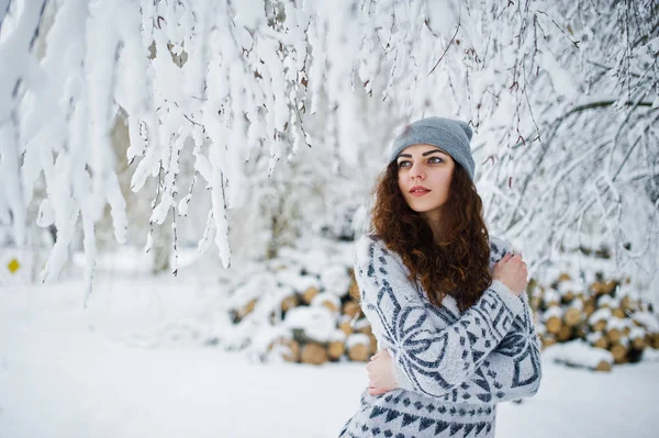 Ładna dziewczyna kręcone w sweter i nakrycia głowy w snowy parku leśnego — Zdjęcie stockowe