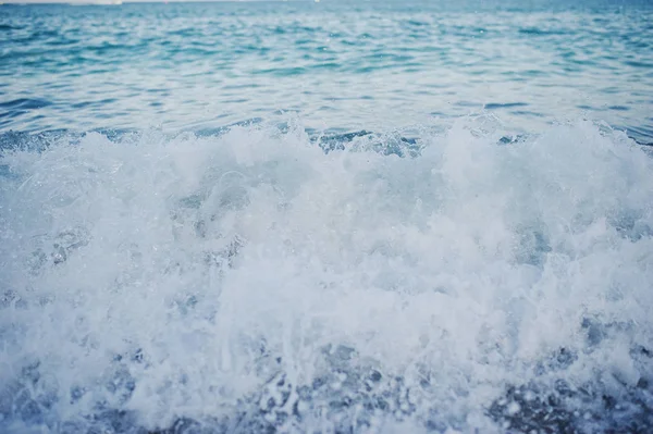 Foto de cerca de las olas que se estrellan en la orilla de la arena . —  Fotos de Stock