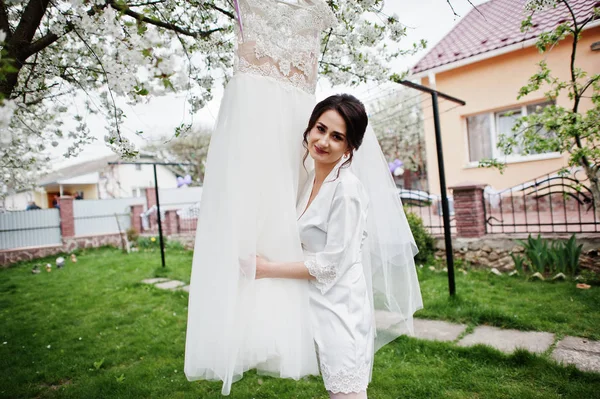 Un portrait d'une jolie mariée posant à côté de sa robe à l'extérieur n — Photo
