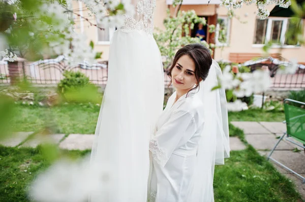 Un portrait d'une jolie mariée posant à côté de sa robe à l'extérieur n — Photo