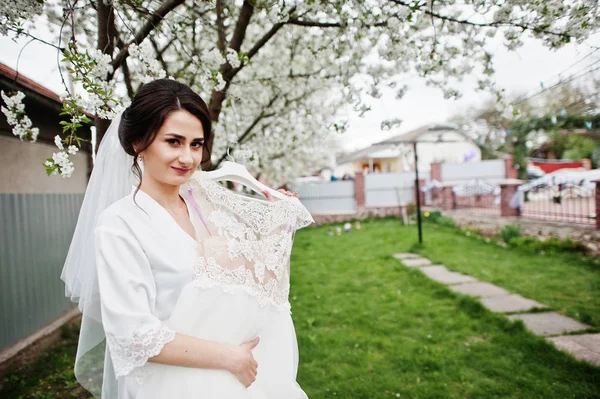 Портрет красивой невесты, позирующей рядом со своим платьем на открытом воздухе — стоковое фото