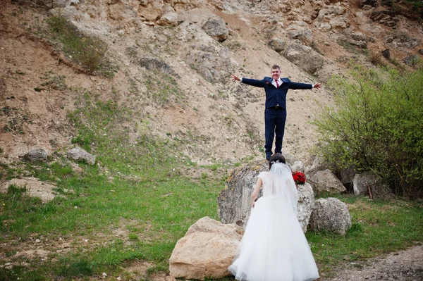 Сумасшедший жених спрыгивает с камня и невеста смотрит на него на свадьбе — стоковое фото