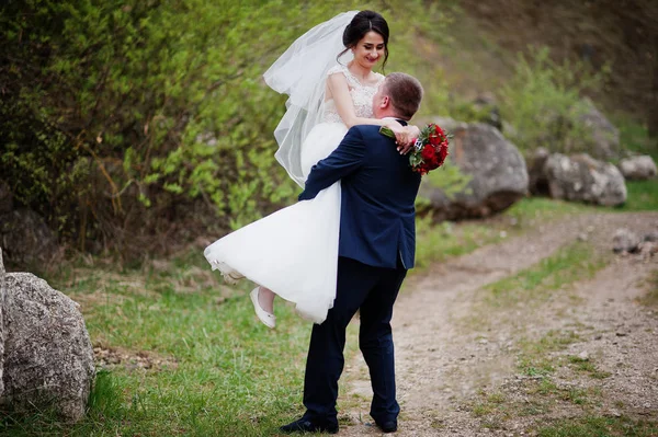 Όμορφος groom κρατώντας και περιστρέφεται γύρω από τη νύφη του κάπου μου — Φωτογραφία Αρχείου