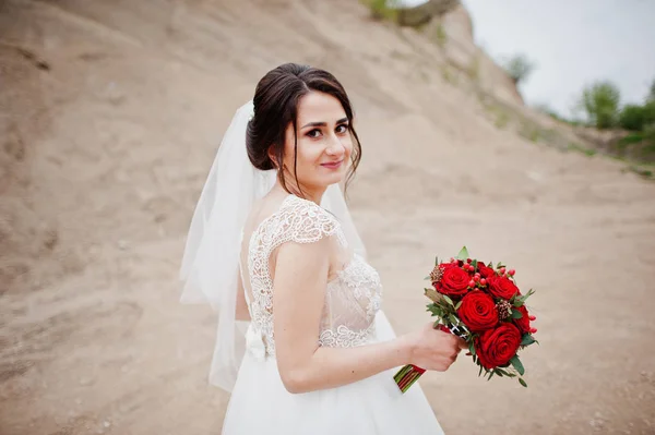 Portrait d'une mariée tenant un bouquet de fleurs rouges et — Photo