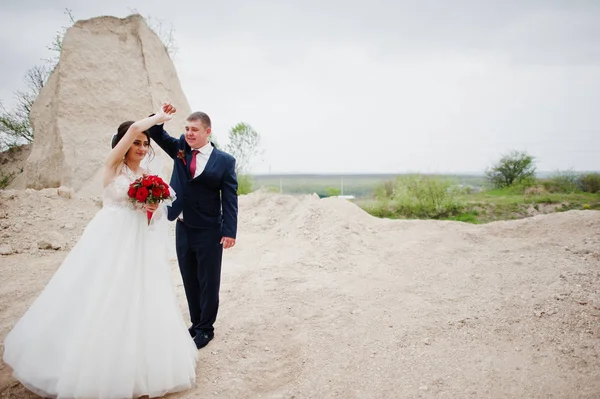 若い結婚式のカップルの結婚式の日の砂の採石場でポーズ. — ストック写真