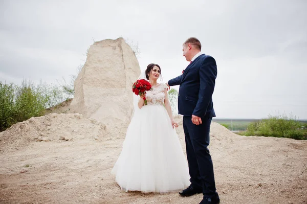 年轻的新婚夫妇摆姿势在采砂在他们的婚礼当天. — 图库照片