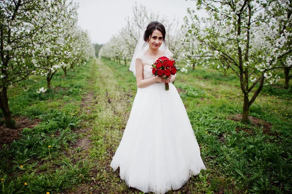 Portréja egy kedves fiatal menyasszony gazdaság piros csokor a virág — Stock Fotó