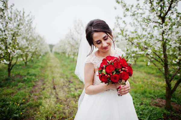 Portrait d'une jeune mariée douce tenant un bouquet rouge dans les fleurs — Photo