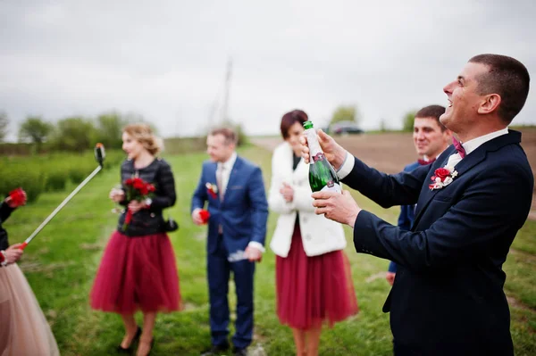 Pareja de bodas, padrino y damas de honor mirando al padrino op — Foto de Stock