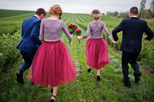 Groomsmen and bridesmaids running in blackcurrant field on a wed — Stock Photo, Image