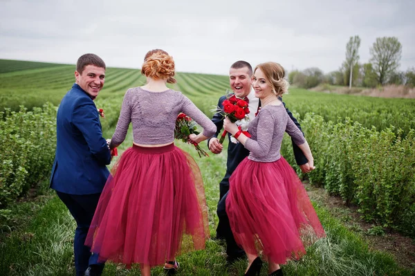 Novios y damas de honor corriendo en el campo de grosella negra en una boda — Foto de Stock