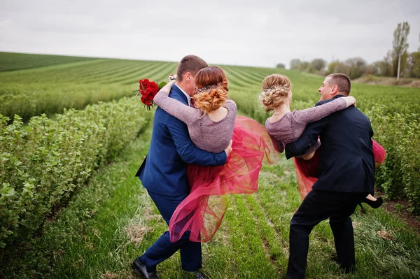 Handsome groomsmen holding bridesmaids and spinning them in blac — Stock Photo, Image